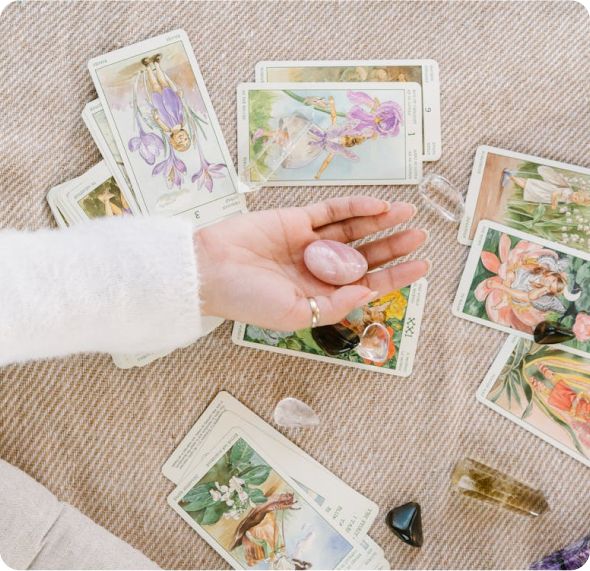 a woman's hand holding a crystal surrounded by tarot cards